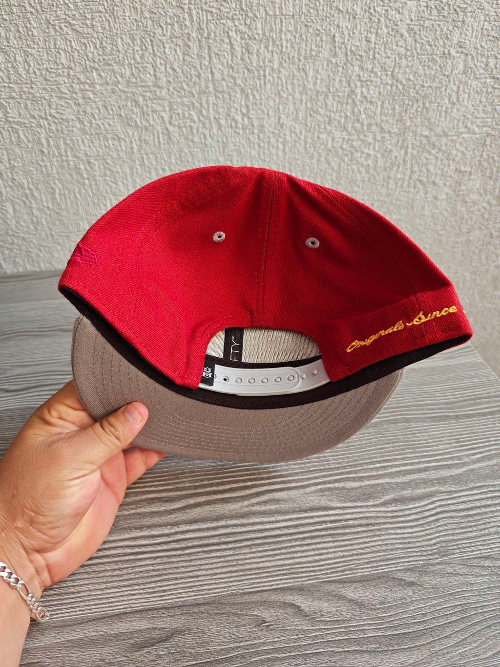 New Era grey and red snapback cap with embroidered "REBEL" anchor design and adjustable strap.
