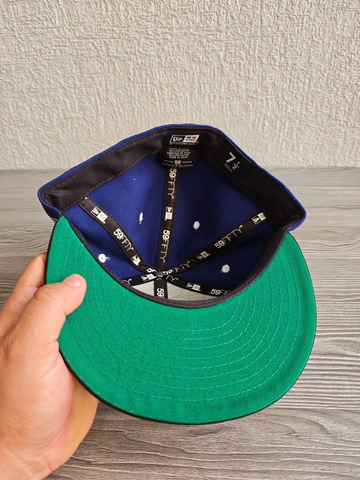 New Era blue and black fitted hat with white embroidered Supra logo and green underside.