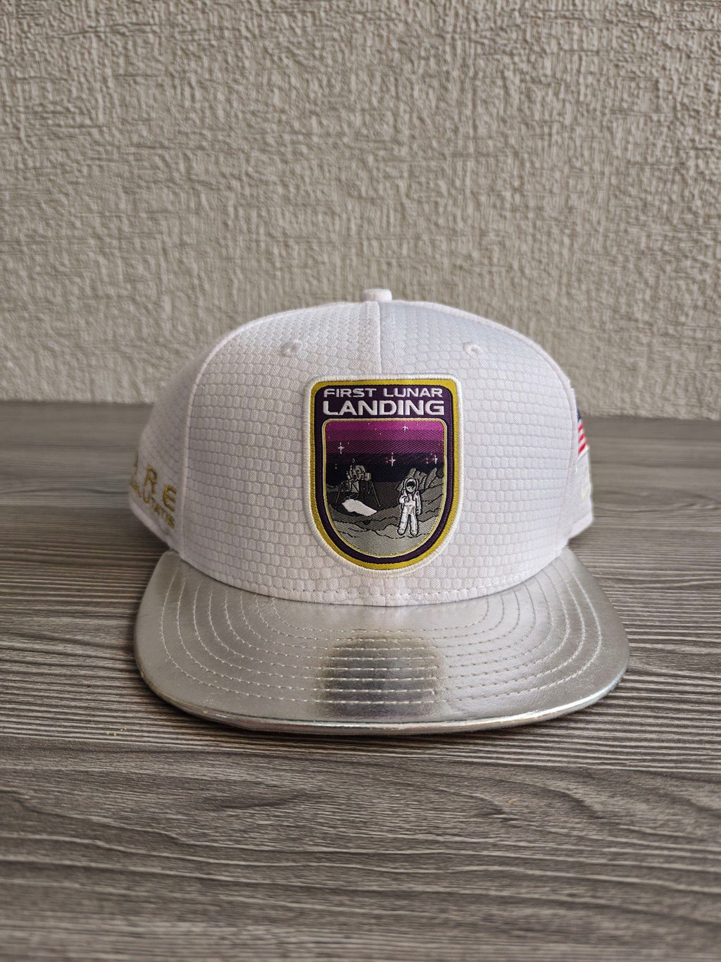 New Era red snapback cap with white textured fabric and embroidered lunar landing patch.