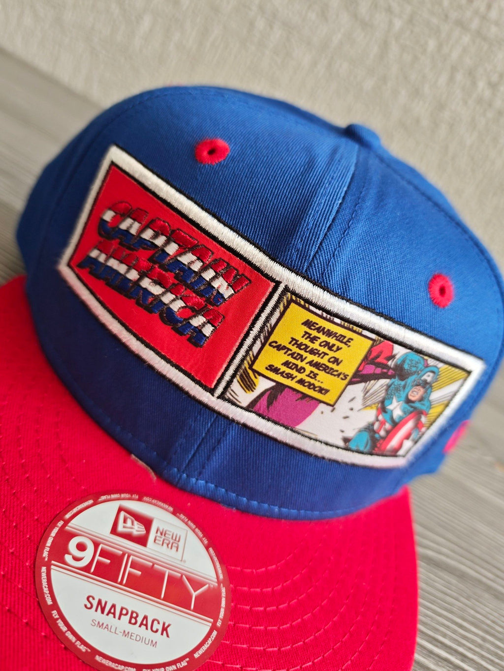 New Era blue and red snapback hat with Captain America comic patch and Marvel logo.