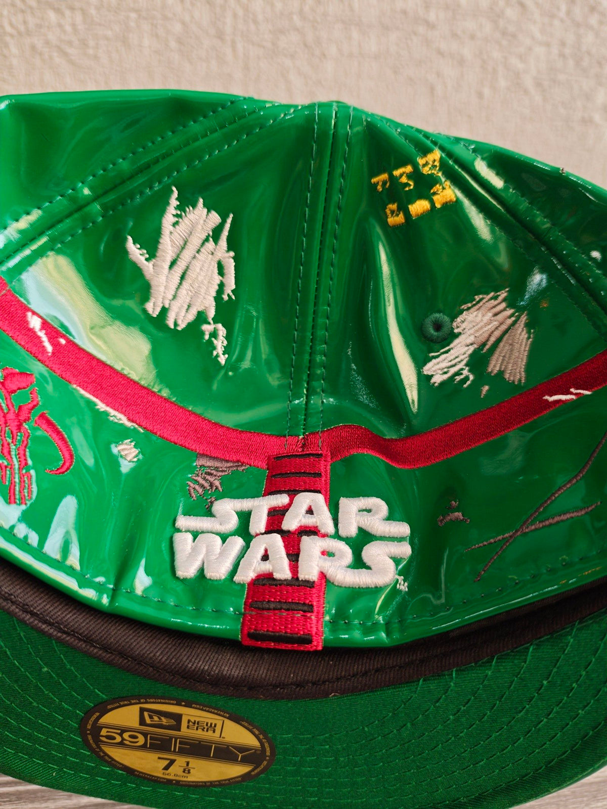 New Era black and green fitted cap with Boba Fett helmet design and space-themed lining.