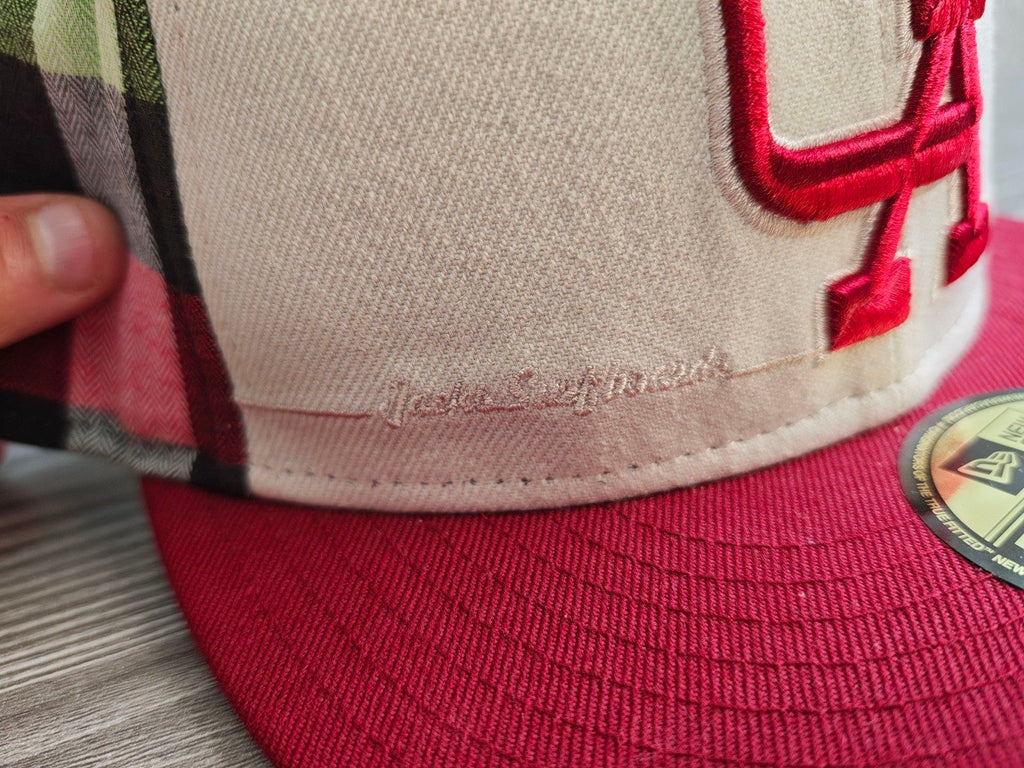 New Era red and cream fitted cap with CA logo and multicolored plaid pattern.