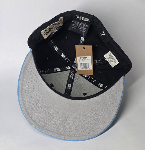 Stüssy black and blue 59FIFTY cap with curly S logo and white detailing.
